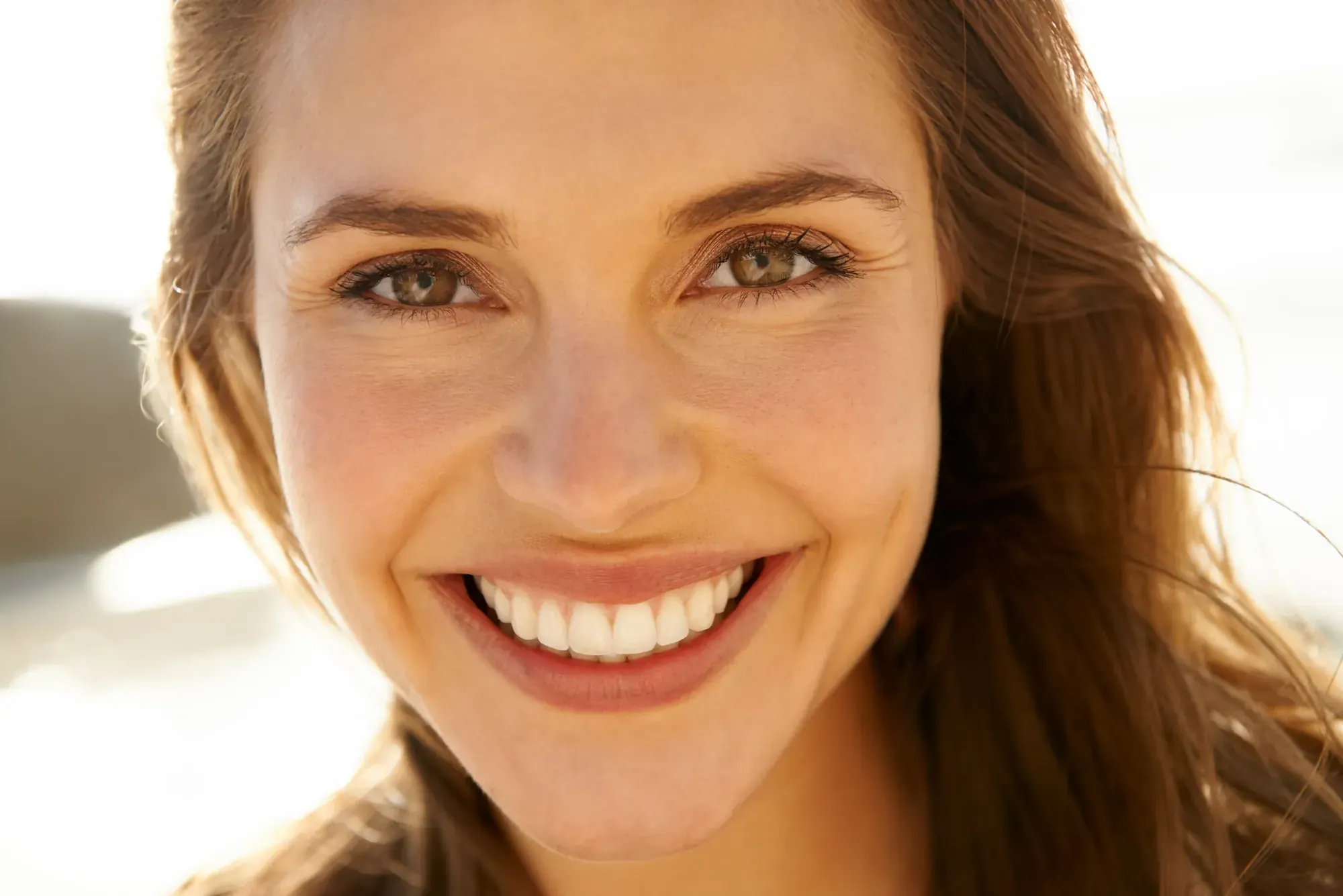 Woman with a bright white smile in soft window light after professional teeth whitening in NYC